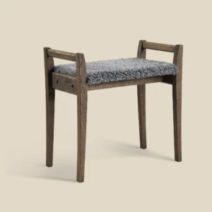 Meja stool in smoked oak with light grey sheepskin on beige background