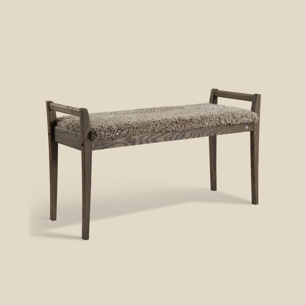 Meja bench in smoked oak with sahara sheepskin on beige background