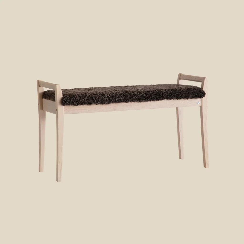 Meja bench in white oiled oak with brown sheepskin on beige background